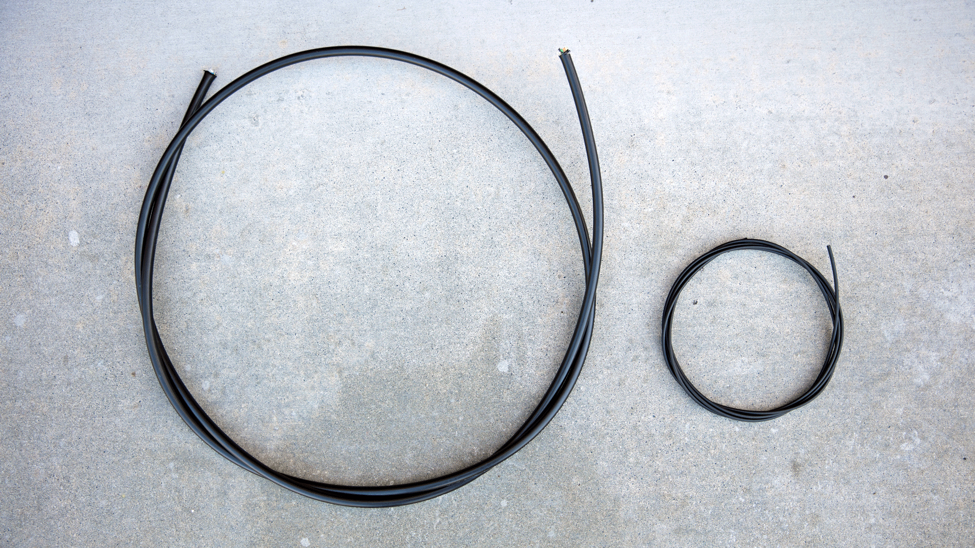 Cable on left is standard aerial fiber optic cable (1 km span weighs ~250 lbs). Cable on right is an equivalent length of the fiber cable developed in this program (1 km span weighs 28 lbs)