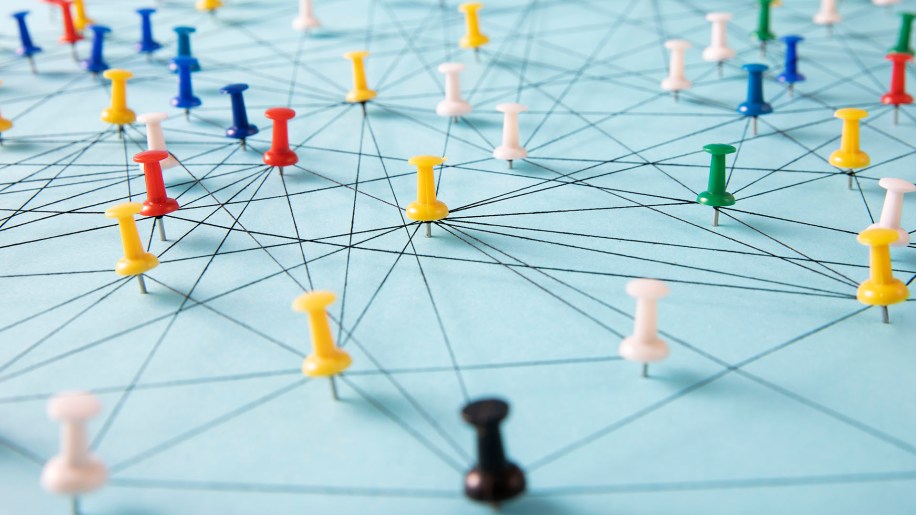 Peering automation at Facebook - An arrangement of colorful pins linked together with string on a pale blue background suggesting a network of connections.